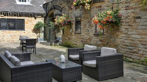 a patio with wicker chairs and a table in front of a building at Best Western Plus Sheffield Mosborough Hall Hotel in Sheffield