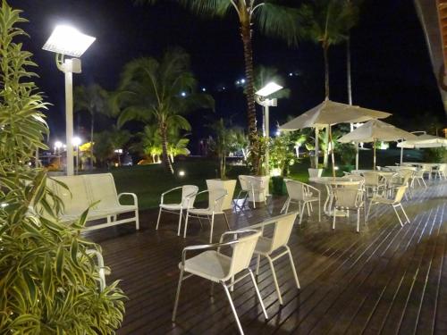 a bunch of chairs and tables with umbrellas at night at Casa Estrela do Mar in Angra dos Reis