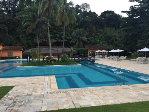 a pool at a resort with tables and umbrellas at Casa Estrela do Mar in Angra dos Reis