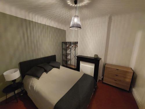 - une chambre avec un lit, une commode et une lampe dans l'établissement Conservatoire - Cours Julien, à Marseille