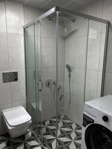 a bathroom with a shower with a toilet and a washing machine at Muzdeniz Life in Gazipasa