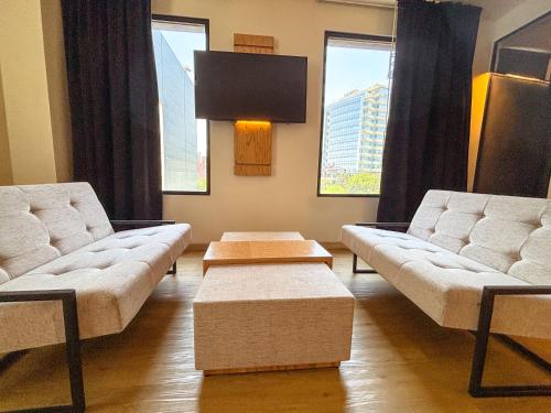 a living room with two white couches and windows at Autentico Monterrey in Monterrey