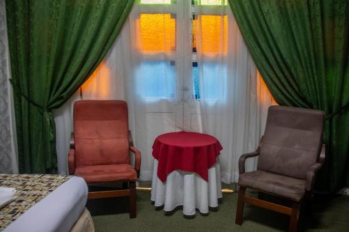 two chairs and a table in a room with curtains at Hotel El Tesoro Sonson in Sonsón