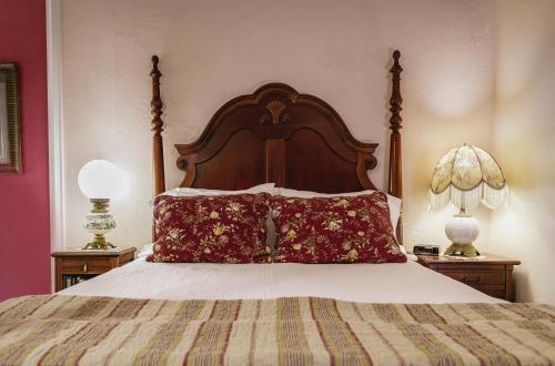 a bed with a large wooden headboard and two lamps at Weaverville Hotel in Weaverville