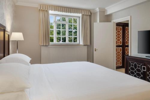a bedroom with a large white bed and a window at Delta Hotels by Marriott St Pierre Country Club in Chepstow