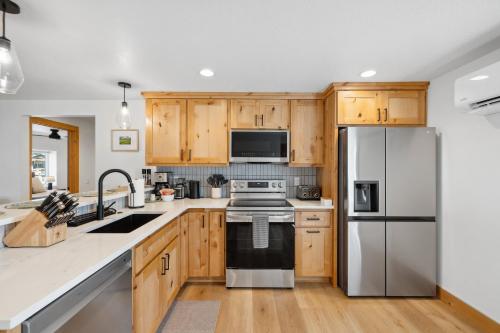 a kitchen with wooden cabinets and a stainless steel refrigerator at New! Brand new Downtown Loft 203 - Lake views, half block from lake, restaurants, and shopping in McCall