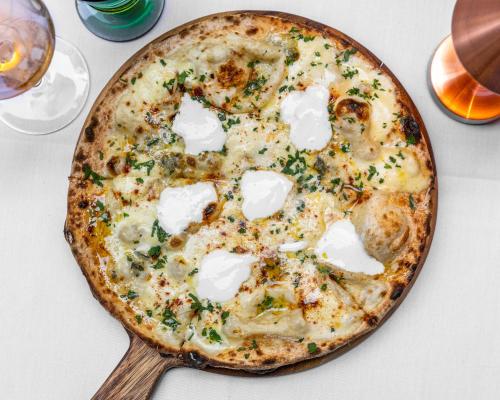 a pizza sitting on top of a table with a wooden spoon at The Sebel Sydney Martin Place in Sydney