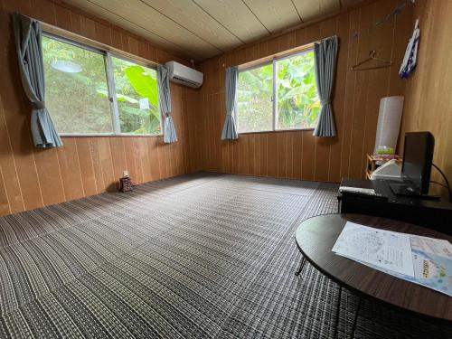 an empty room with a table and two windows at やどバンブー in Hateruma