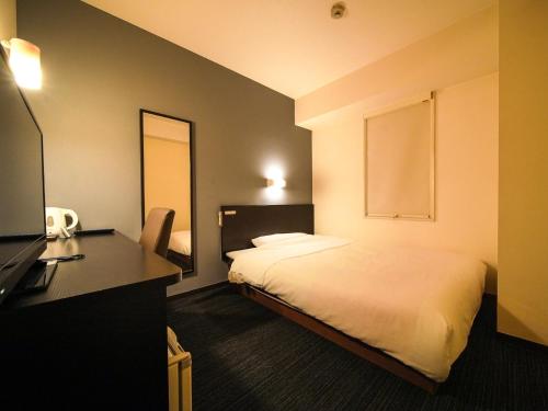 a hotel room with a bed and a desk with a desk at Super Hotel Okazaki in Okazaki