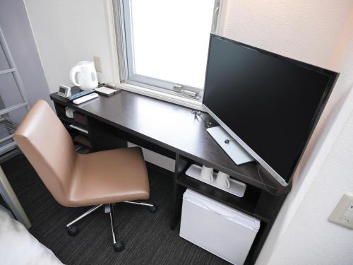 a desk with a monitor and a chair in a room at Super Hotel Okazaki in Okazaki