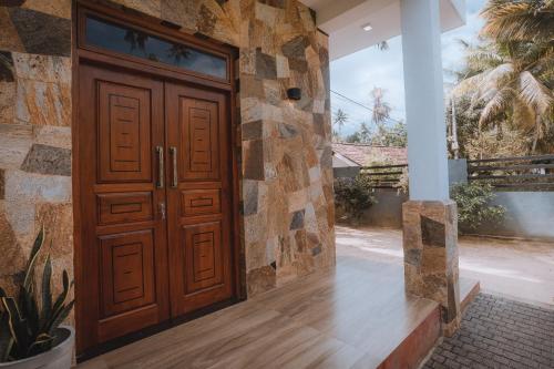 a wooden door in a house with a stone wall at RIU Villa & Apartment in Matara