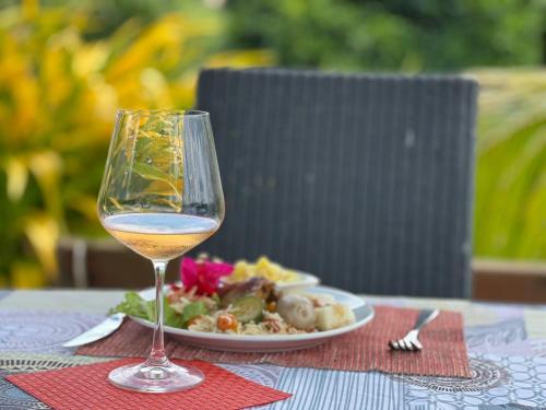 una copa de vino sentada en una mesa con un plato de comida en Passion Du Paradis972, en Rivière-Pilote