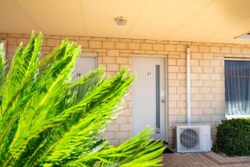 a brick house with palm trees in front of it at Bunbury Motel and Apartments in Bunbury