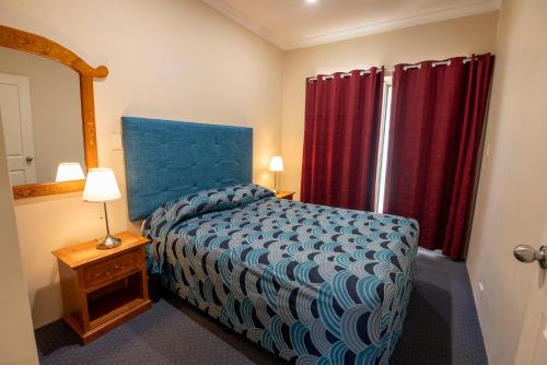 a bedroom with a bed and a red curtain at Bunbury Motel and Apartments in Bunbury