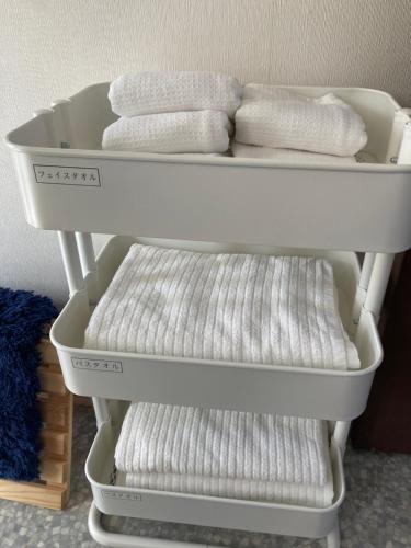 four white towels are on a white shelf at シテコベハウス in Yokosuka