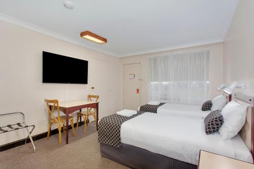 a hotel room with a bed and a table at Econo Lodge Savannah Park Tamworth in Tamworth