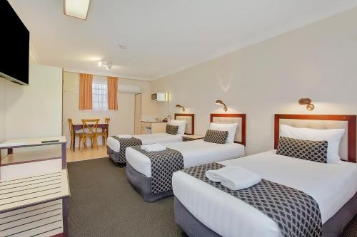 a hotel room with three beds and a television at Econo Lodge Savannah Park Tamworth in Tamworth