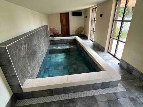- une piscine dans un bâtiment doté de carrelage dans l'établissement Gîte de charme avec spa, piscine intérieure et jardin clos près de Chinon - FR-1-381-553, à Beaumont-en-Véron