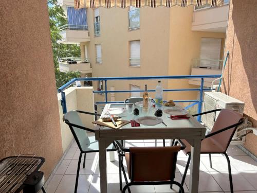une table et des chaises sur le balcon d'un bâtiment dans l'établissement Appartement cosy à Port Fréjus: climatisé, proche plage, commerces et garage - 4 couchages - FR-1-226A-176, à Fréjus