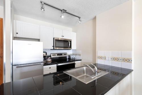 a white kitchen with a sink and a microwave at The Aspens by Whiski Jack in Whistler