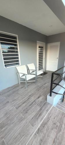 a room with two white chairs and a wooden floor at A modern and cozy 2 bedroom apartment in Willemstad