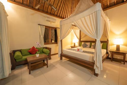 a bedroom with a canopy bed and a couch at Villa Unique in Ubud