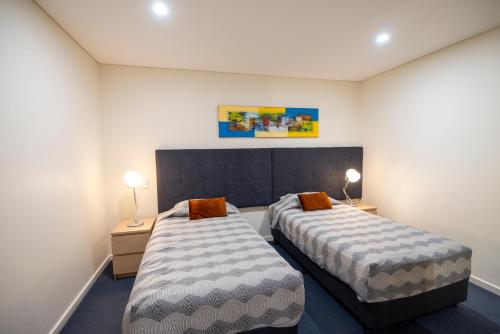 two beds in a small room with two lamps at Bunbury Motel and Apartments in Bunbury