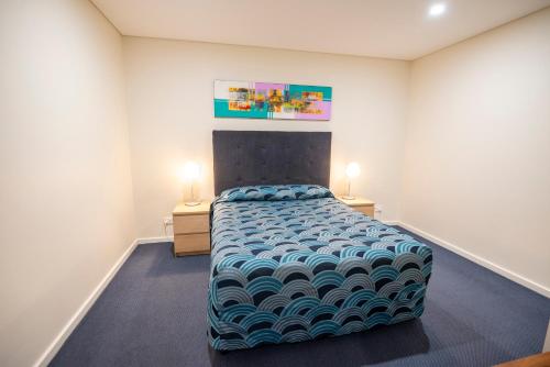 a bedroom with a large bed in a room with two lamps at Bunbury Motel and Apartments in Bunbury