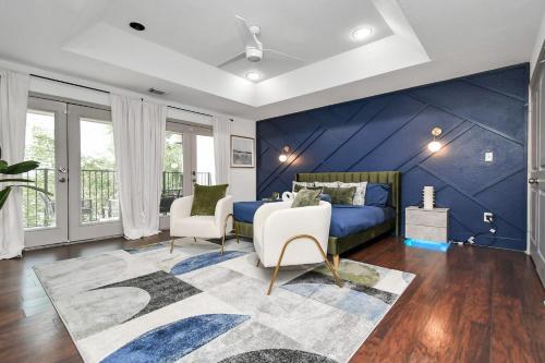 a blue bedroom with a bed and two chairs at ProlificSuites Escape - Stylish Spaces & Prime Location in Houston