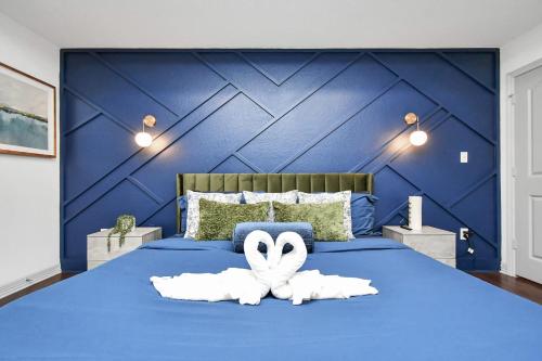 a blue bed with two white towels on it at ProlificSuites Escape - Stylish Spaces & Prime Location in Houston
