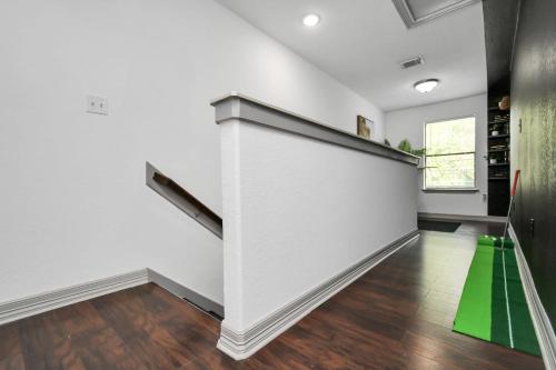 a hallway with white walls and a staircase with a green cone at ProlificSuites Escape - Stylish Spaces & Prime Location in Houston