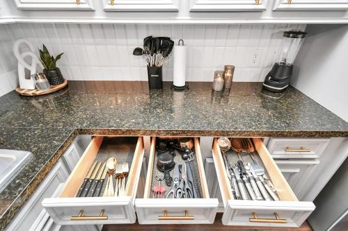 a kitchen counter with a drawer filled with utensils at ProlificSuites Escape - Stylish Spaces & Prime Location in Houston