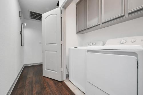 a white laundry room with a washer and dryer at ProlificSuites Escape - Stylish Spaces & Prime Location in Houston