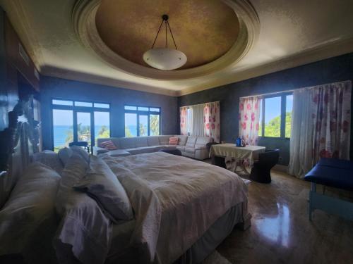 a bedroom with a large bed and a couch at Villa Tesoros del Mar - Luxury Beachfront Villa with Natural Pool, Jacuzzi, Mountain Views, Yoga, BBQ, Wi-Fi, Pet & Family Friendly, Barahona Adventures in El Arroyo