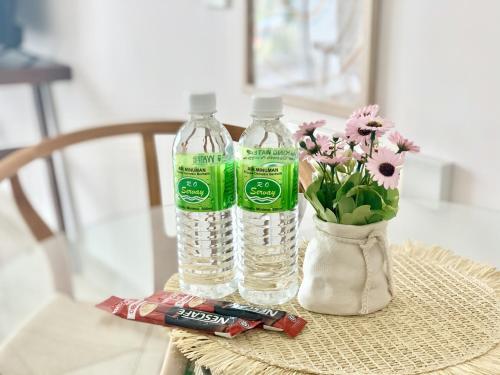 a table with two bottles of water and a vase of flowers at Deco Home @ Aru Suites in Kota Kinabalu