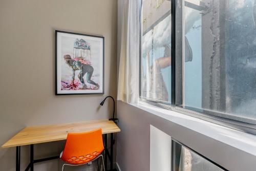 a room with a table and a orange chair next to a window at The Constance Fortitude Valley in Brisbane