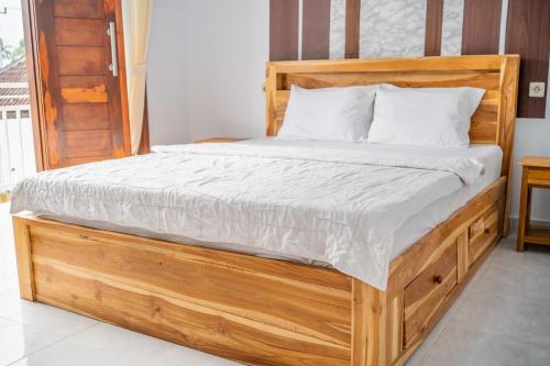 un letto in legno con lenzuola e cuscini bianchi di Twin OLA a Tabanan