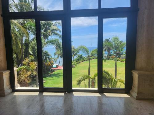 an open window with a view of palm trees at Villa Tesoros del Mar - Luxury Beachfront Villa with Natural Pool, Jacuzzi, Mountain Views, Yoga, BBQ, Wi-Fi, Pet & Family Friendly, Barahona Adventures in El Arroyo