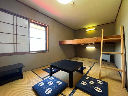 a room with bunk beds and a desk and a table at Pension Mon Repos in Nozawa Onsen