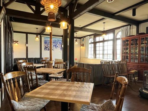 a restaurant with wooden tables and chairs and windows at Pension Mon Repos in Nozawa Onsen