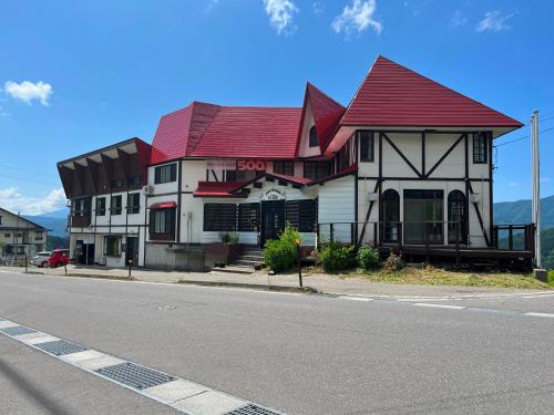 a building with a red roof on the side of a street at Pension Mon Repos in Nozawa Onsen
