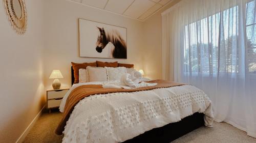 a bedroom with a bed with a horse picture on the wall at Rustling Oaks NZ Boho Pool House in Cambridge