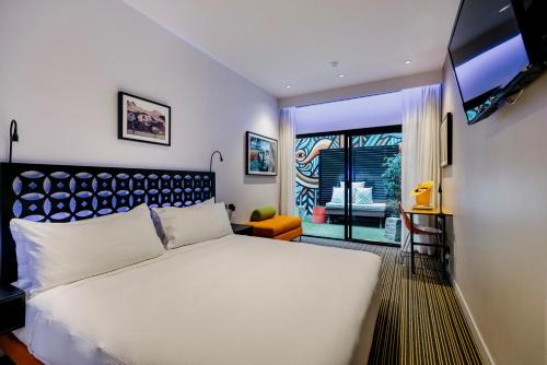a bedroom with a large white bed and a window at The Constance Fortitude Valley in Brisbane