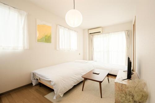a white bedroom with a bed and a table at Mi-APT MIDORI in Tokyo