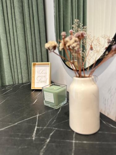 a candle and a vase with flowers and a box at Panoramic Ultracentral Apartment Rădăuți ACR in Rădăuţi