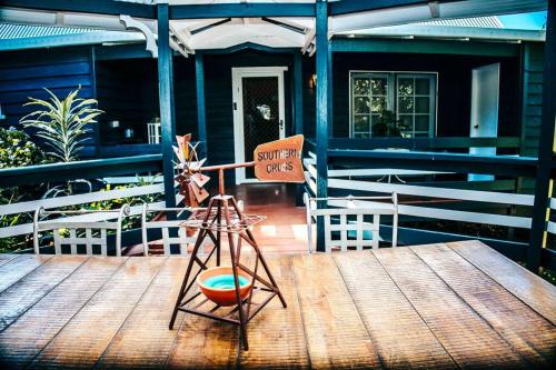 a wooden table with a sign on the front of a house at Gorgeous 3 bedroom raked ceiling cabin on the hill in Blackbutt