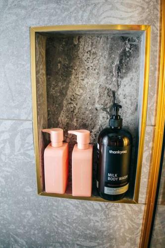 a shelf with three bottles of soap in a bathroom at Gorgeous 3 bedroom raked ceiling cabin on the hill in Blackbutt