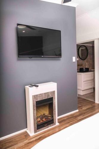 a living room with a fireplace with a tv on the wall at Gorgeous 3 bedroom raked ceiling cabin on the hill in Blackbutt