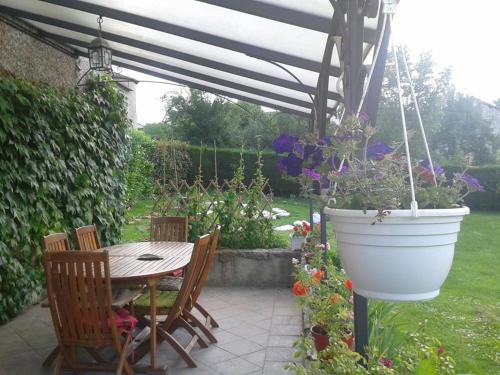 une terrasse avec une table et un pot de fleurs dans l'établissement Aloha, à Montjoie-en-Couserans