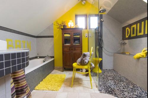 a teddy bear sitting on a yellow chair in a bathroom at La petite maison dans la campagne in Massingy-lès-Vitteaux